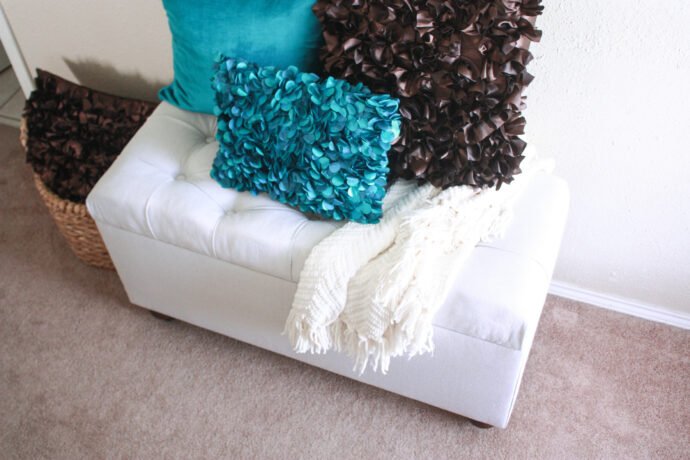 Top shot of the bench with a blanket draped over the bench and throw pillows too