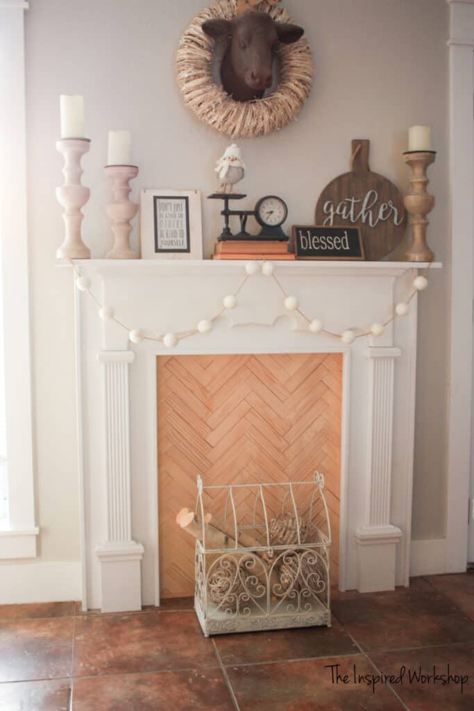 DIY faux fireplace decorated with candles and a gather sign, a scale and some wood in a house