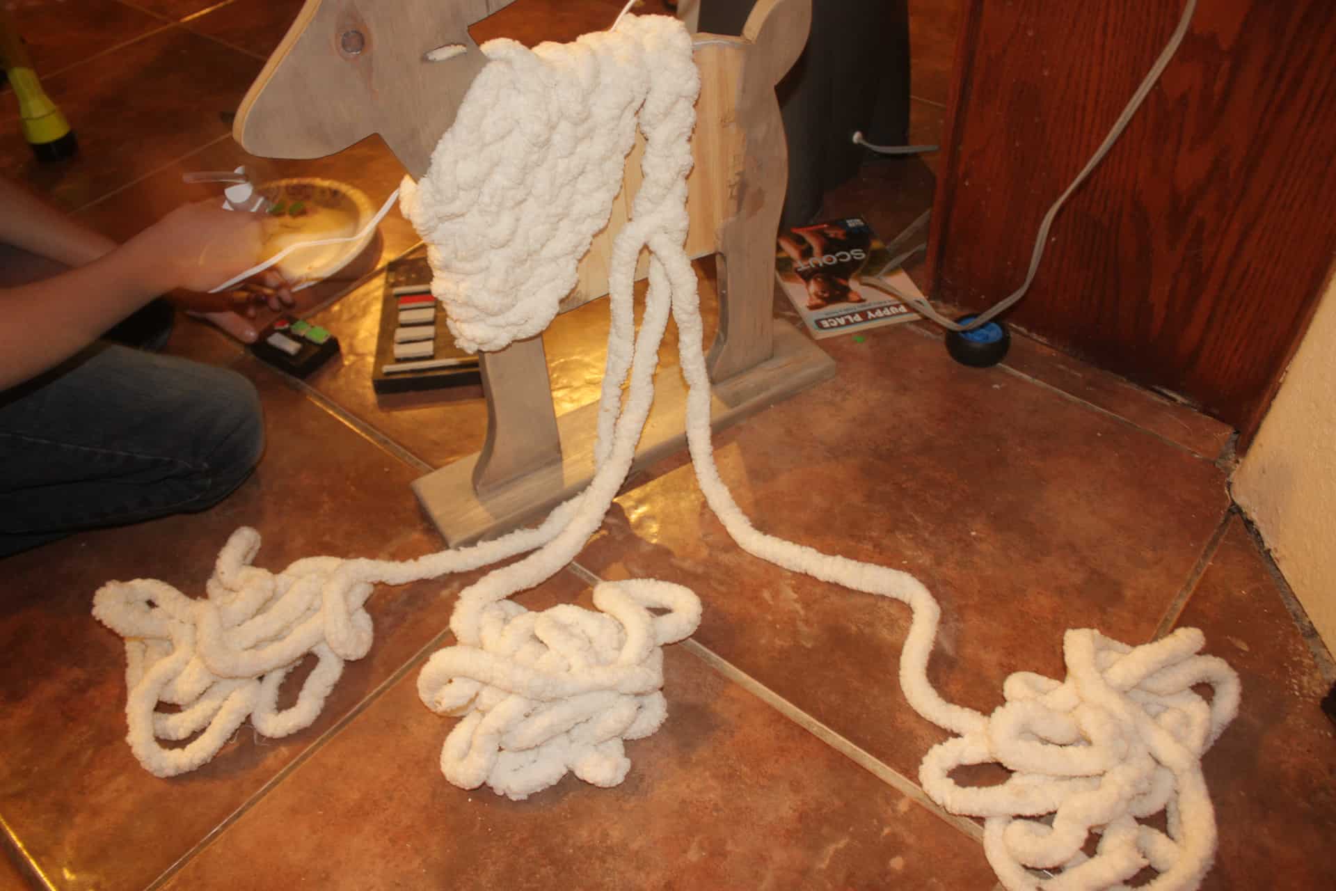 DIY wood deer being made with yarn on the ground as it is being braided and wrapped