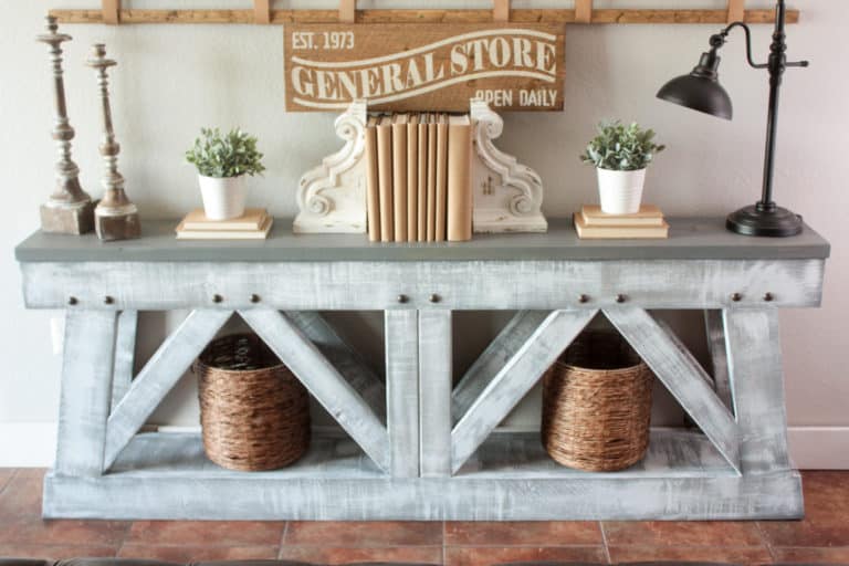 Gray and White Truss DIY Console Table with books and plants some candle sticks and a black lamp