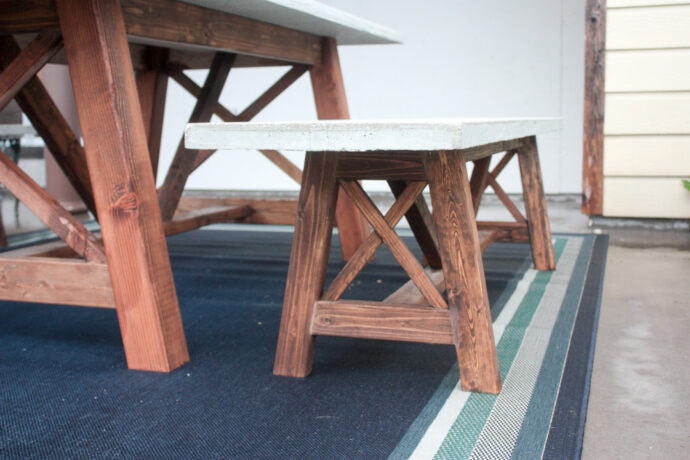 Concrete Dining Bench sitting beside dining table and on top of navy blue rug