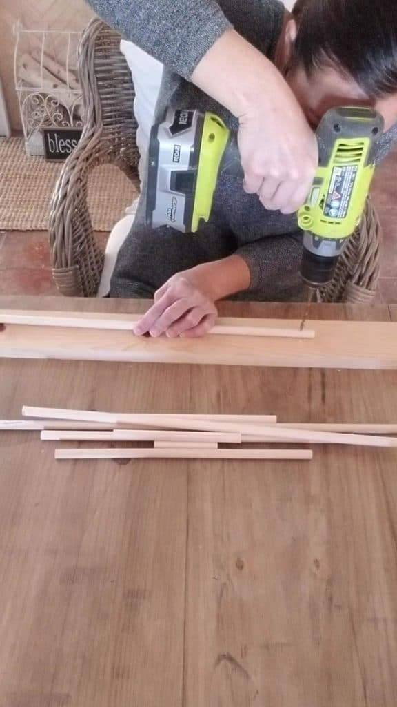 making the DIY christmas card holder drilling holes in the dowel rods to make the tree of tassels