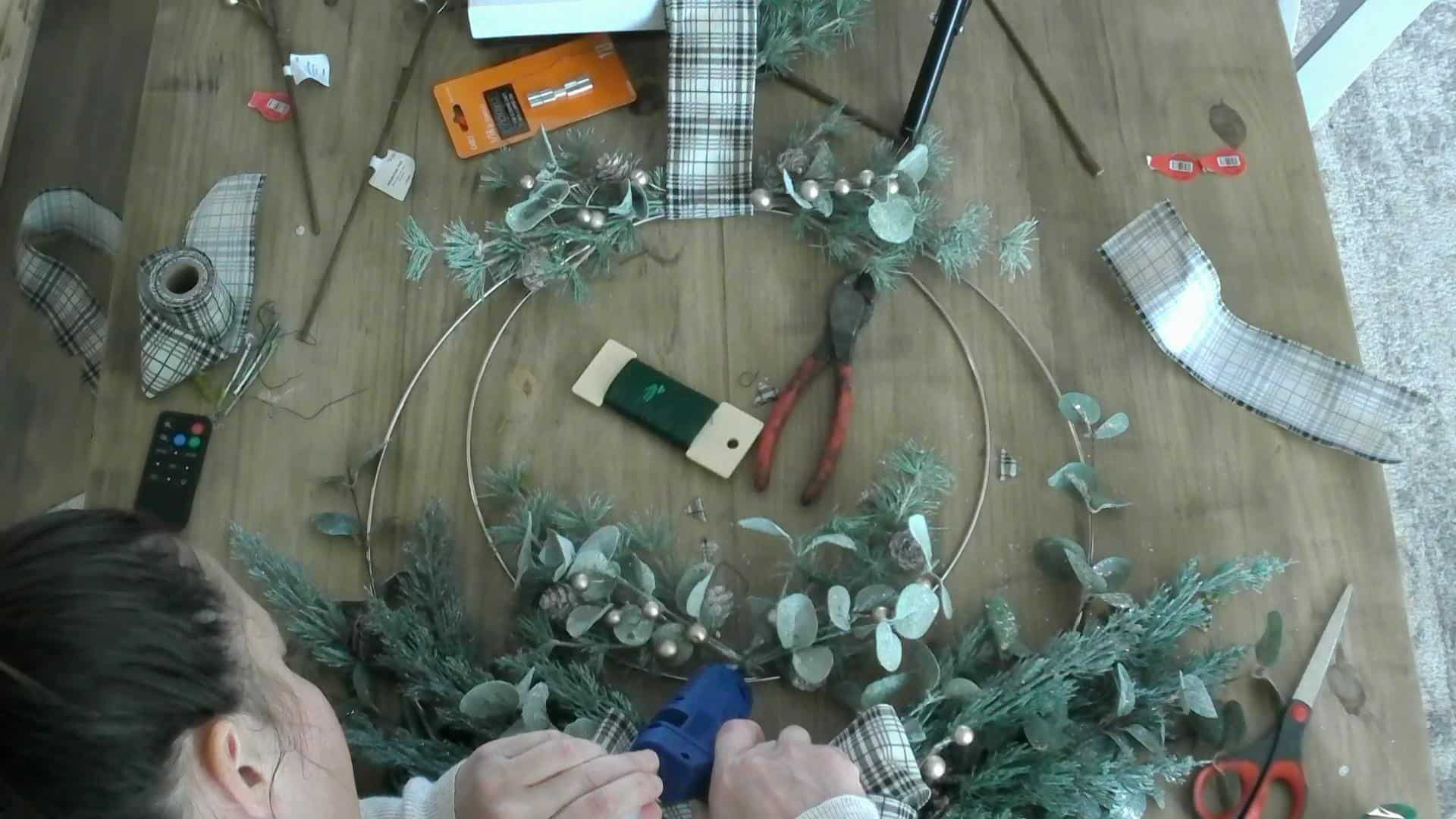 Hot glueing the stems into place on the DIY Christmas Wreath