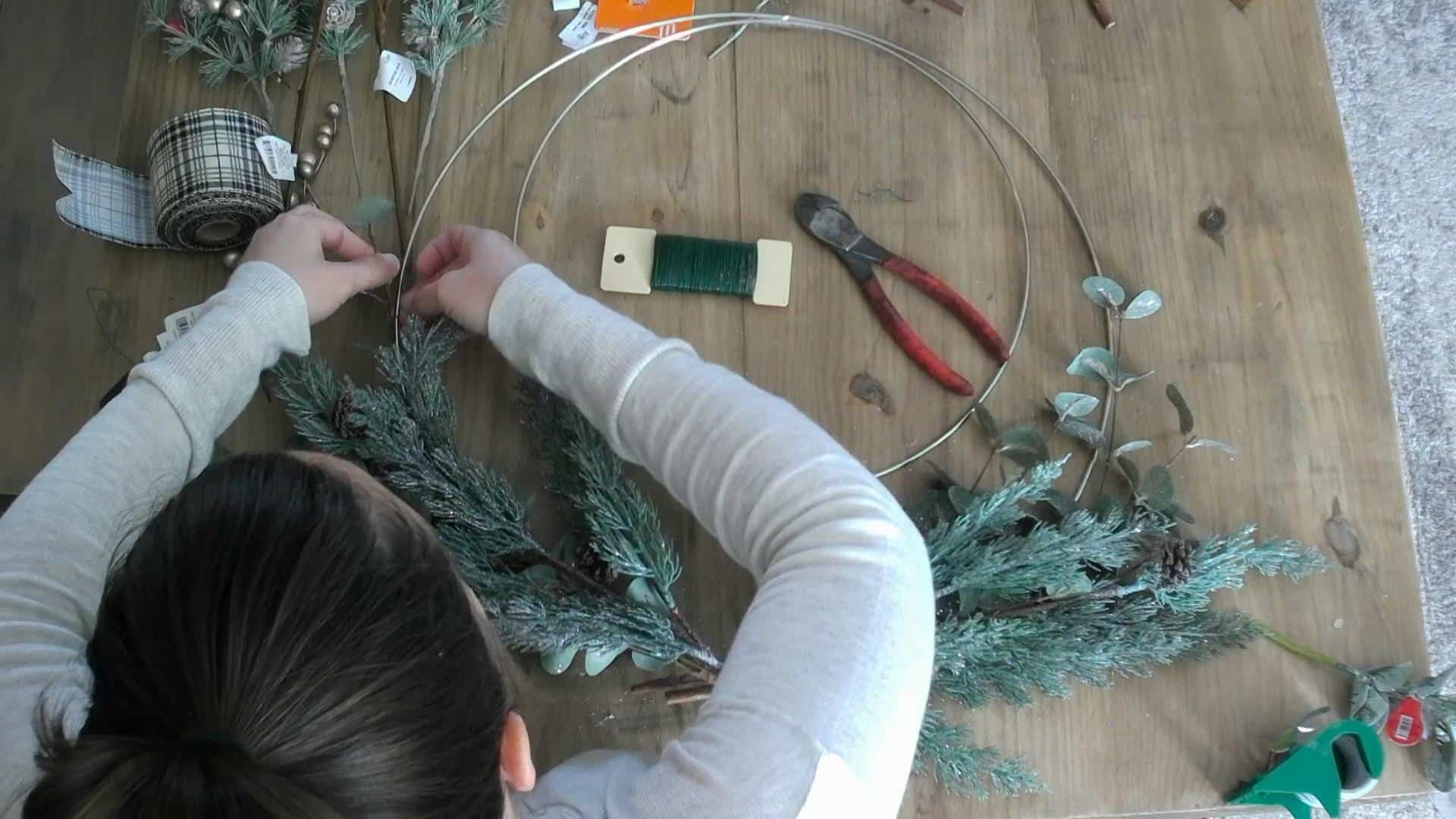 Adding the greenery to the DIY christmas / winter wreath