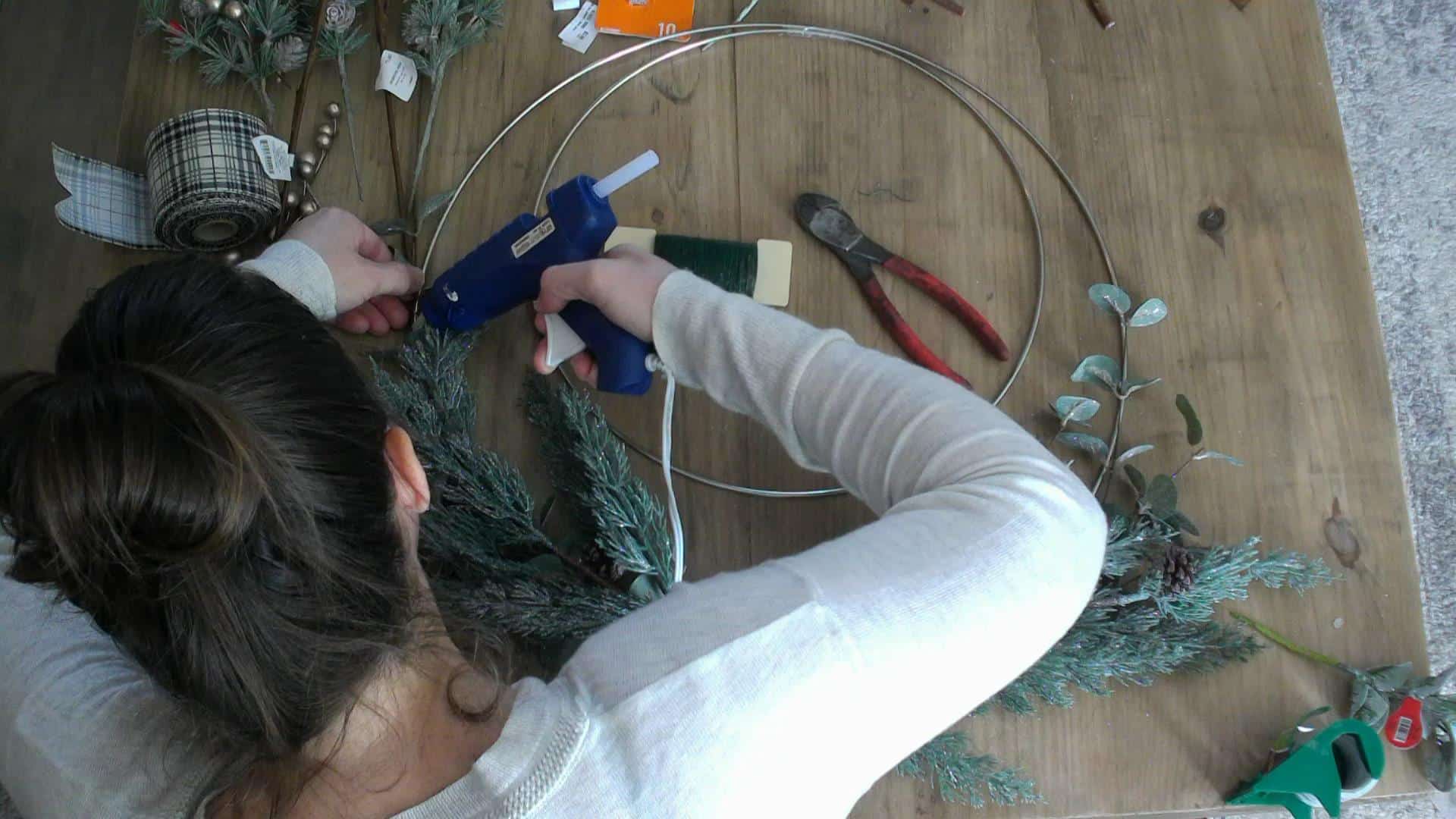 Hot gluing the greenery to the metal hoop wreath