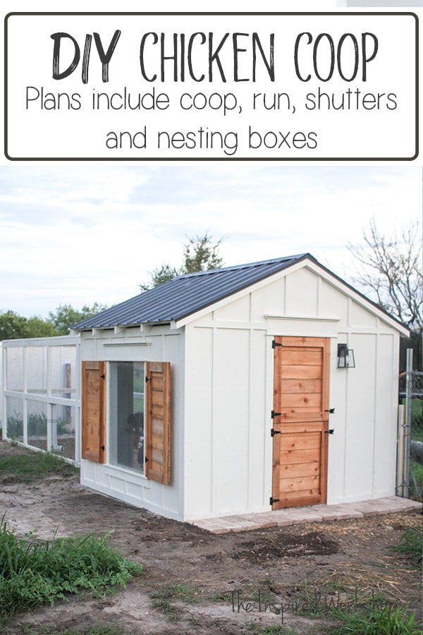 Picture of the front of the chicken coop white with cedar door and shutters on the window and a gray metal roof