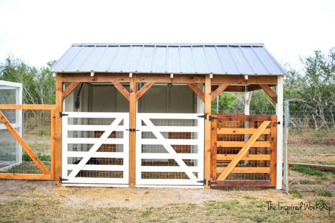 Goat House with two white gates and one cedar gate with cedar posts and tin roof