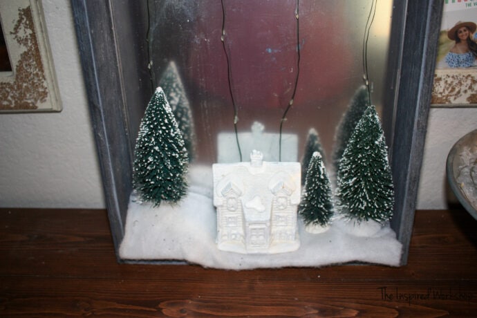 CHristmas shadow box up close of the ceramic house and bottle brush trees