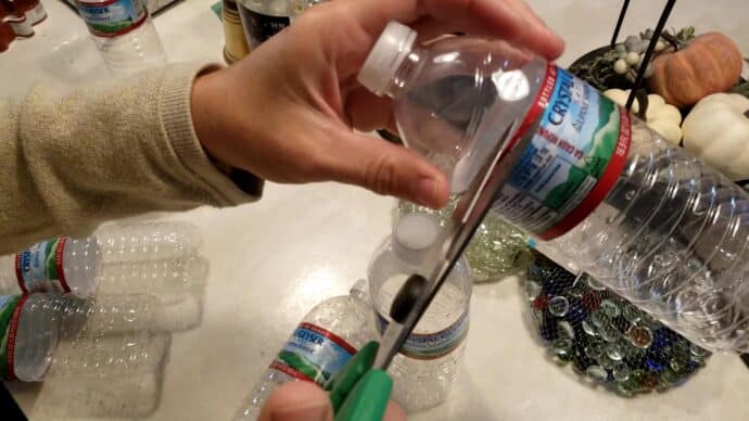 Cutting the top off of a water bottle to make the DIY Christmas Bells