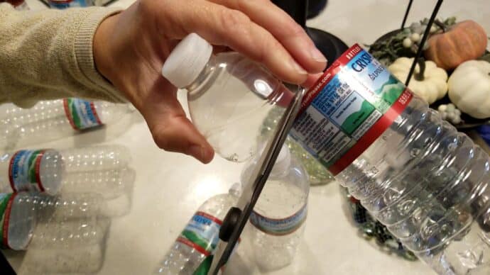 Cutting the top off of a water bottle to make christmas bells