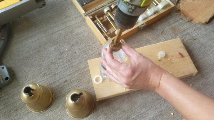 Drilling a hole in a water bottle lid to be the ring on our bell