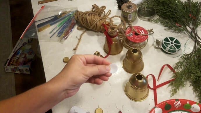 Adding a small piece of plastic to cover the hole on the DIY Christmas bells