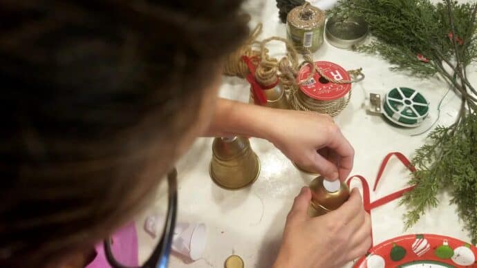 Hot glueing the small piece of plastic to cover the hole on the christmas bells