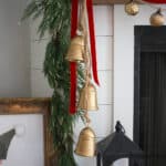 DIY Christmas Bells hanging from the fireplace mantel with red velvet ribbon