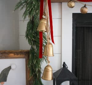 DIY Christmas Bells hanging from the fireplace mantel with red velvet ribbon