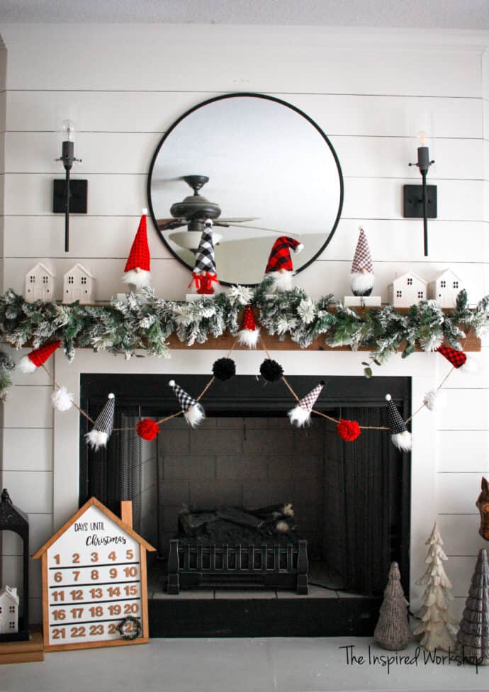 DIY Gnome garland hanging from the fireplace mantel with advent calender and gnome stocking holders and a flocked Christmas garland as wellgarland