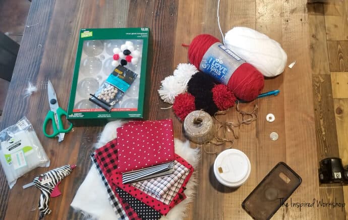 Supplies for the DIY Christmas Garland with gnomes - yarn, ornaments, fabric, fur, wooden beads, twine, coffe, glue gun, scissors