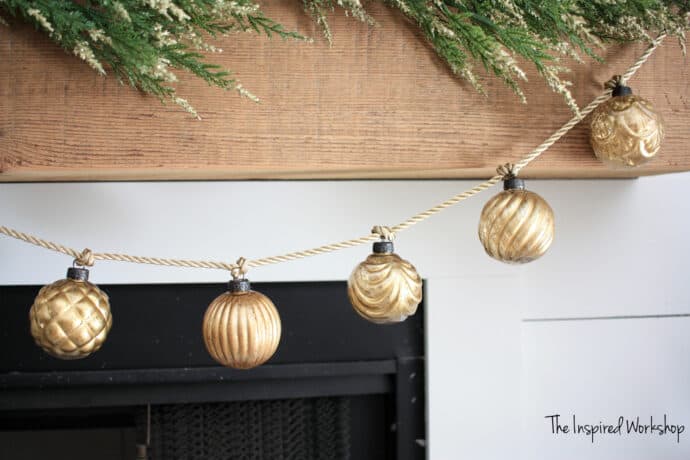 DIY Garland made of gold mercury glass ornaments hanging on the mantel