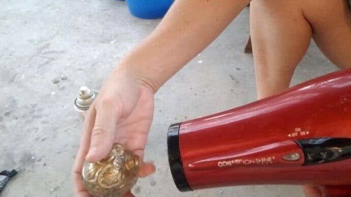 blow drying the ornament to make diy mercury glass ornaments for christmas