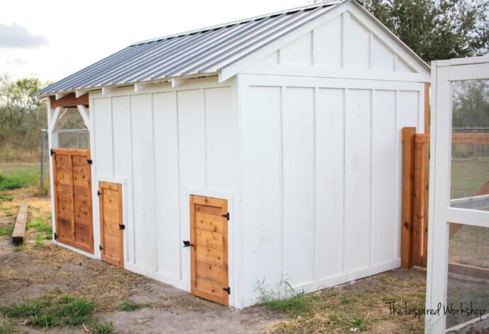 DIY Goat House back view with small doors and large gate to the left