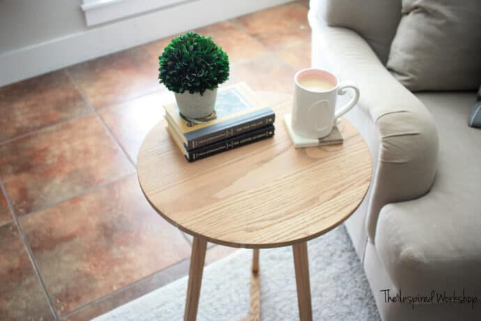 DIY side table with round top and a couple books with a plant on top with a cup of coffee