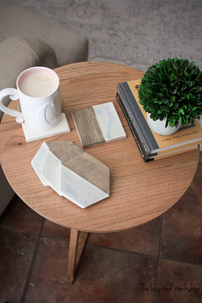 Epoxy Resin Coasters that have wood and the marble epoxy sitting on a table with books and coffee