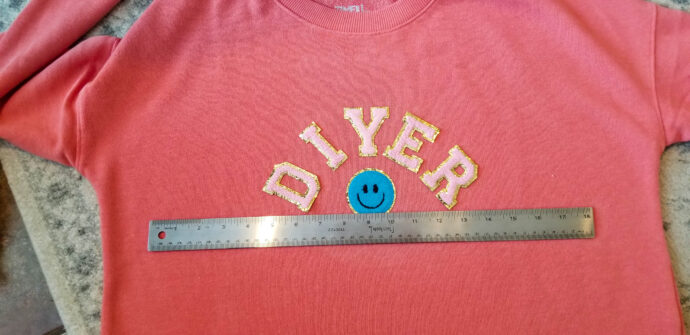 Using a ruler to line up the letters on the sweatshirt