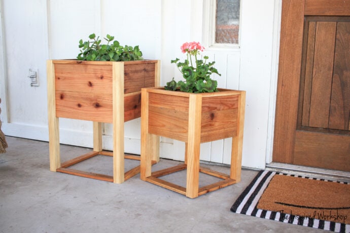 Small and Larger matching planter boxes sitting by front door with flowers and plants in them