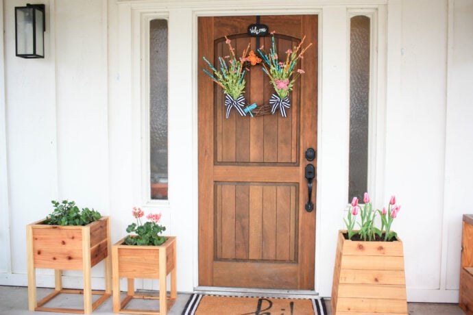 Wreath for spring on the door, planters to the left and right of the door with spring flowers