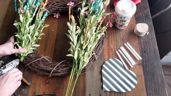 hot gluing the bunch of flowers into place on the wreath