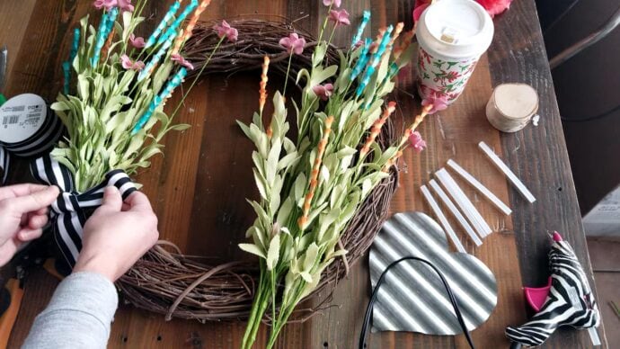 tying the ribbon into a bow on the flower bunch on the spring wreath