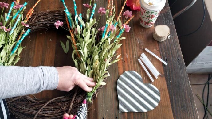 Making the DIY wreath for spring using hot glue to attach the flower bunch