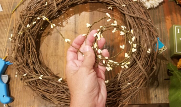 adding a small garland to the grapevine wreath form