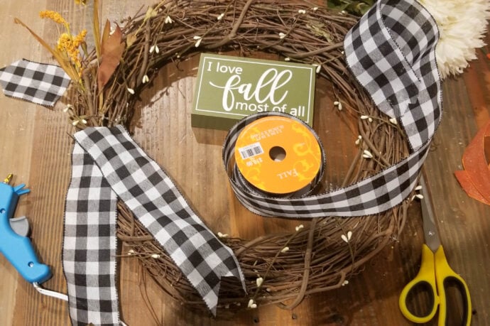 adding the tails of the bow to the wreath underneath the actual bow on the DIY fall wreath