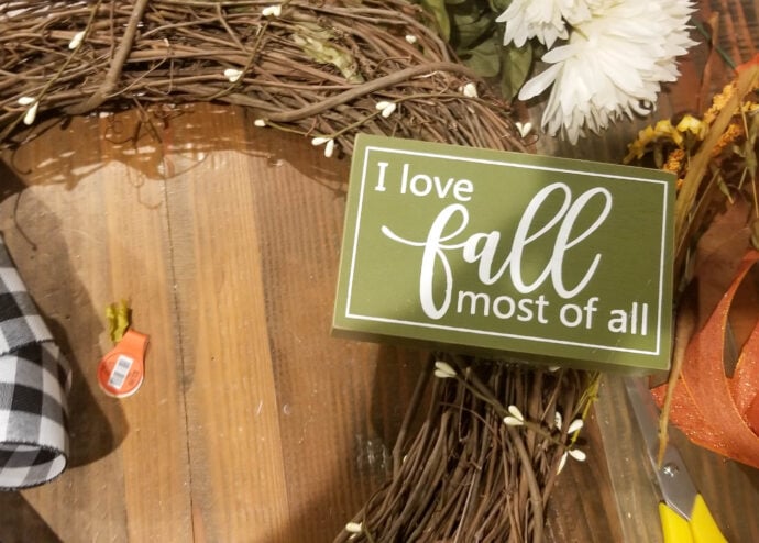 adding the "I love fall most of all" sign to the fall wreath