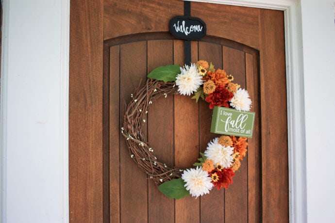 DIY grapevine wreath for fall on a wood door with a welcome wreath hanger