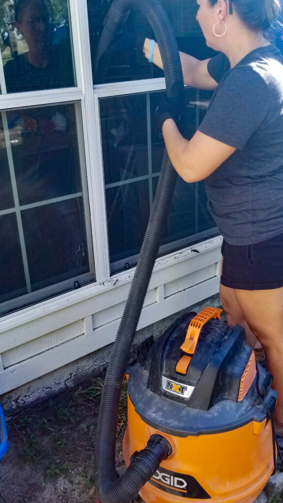 vacuuming out the window frame in preparation of the new window glass