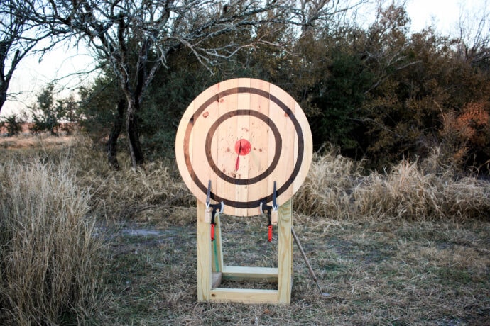 DIY axe throwing target with axes and throwing knives on it