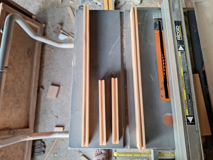 Boards to make the frame of the cabinet door laying on a table saw