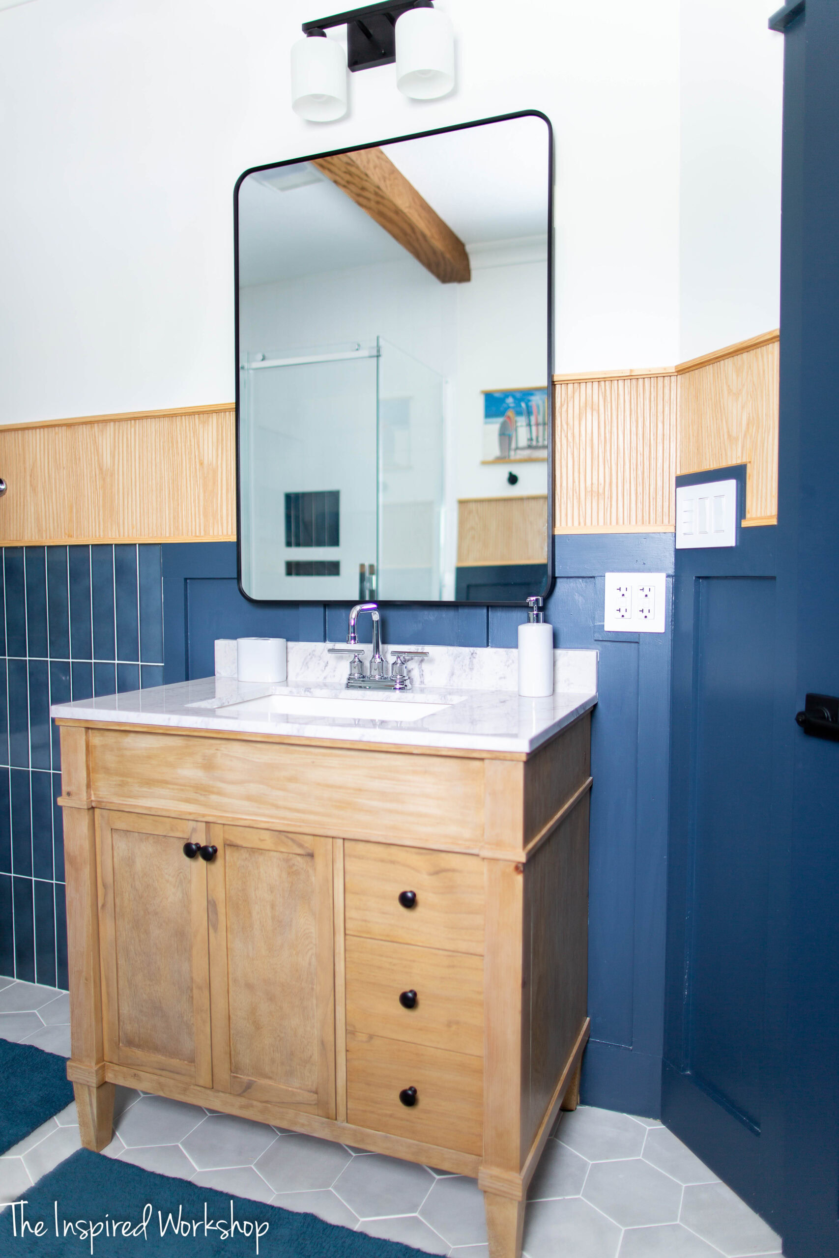 image of bathroom vanity in a light colored wood with a black metal framed mirror hanging above it