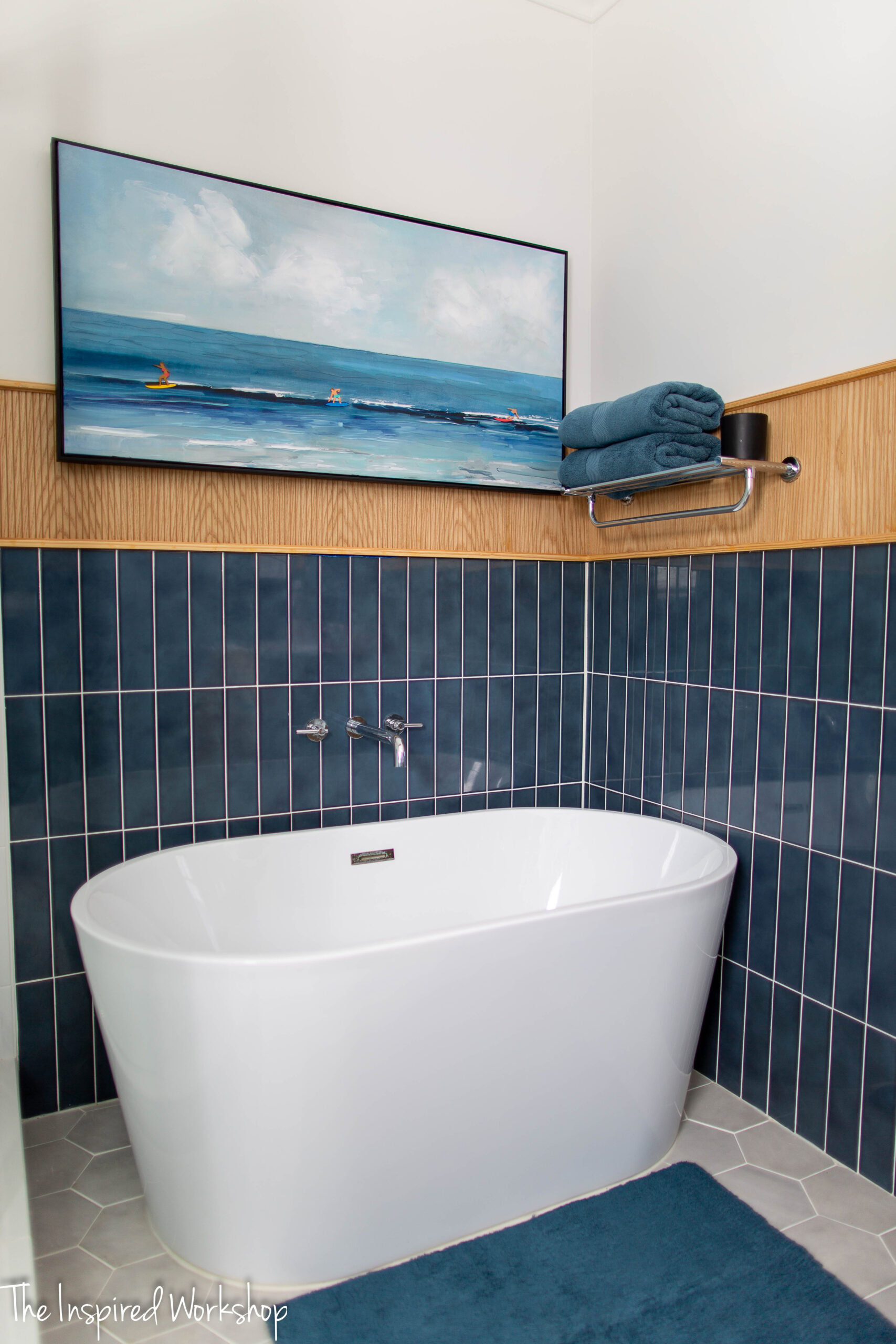 Free standing bathtub with navy blue tile and a chrome faucet