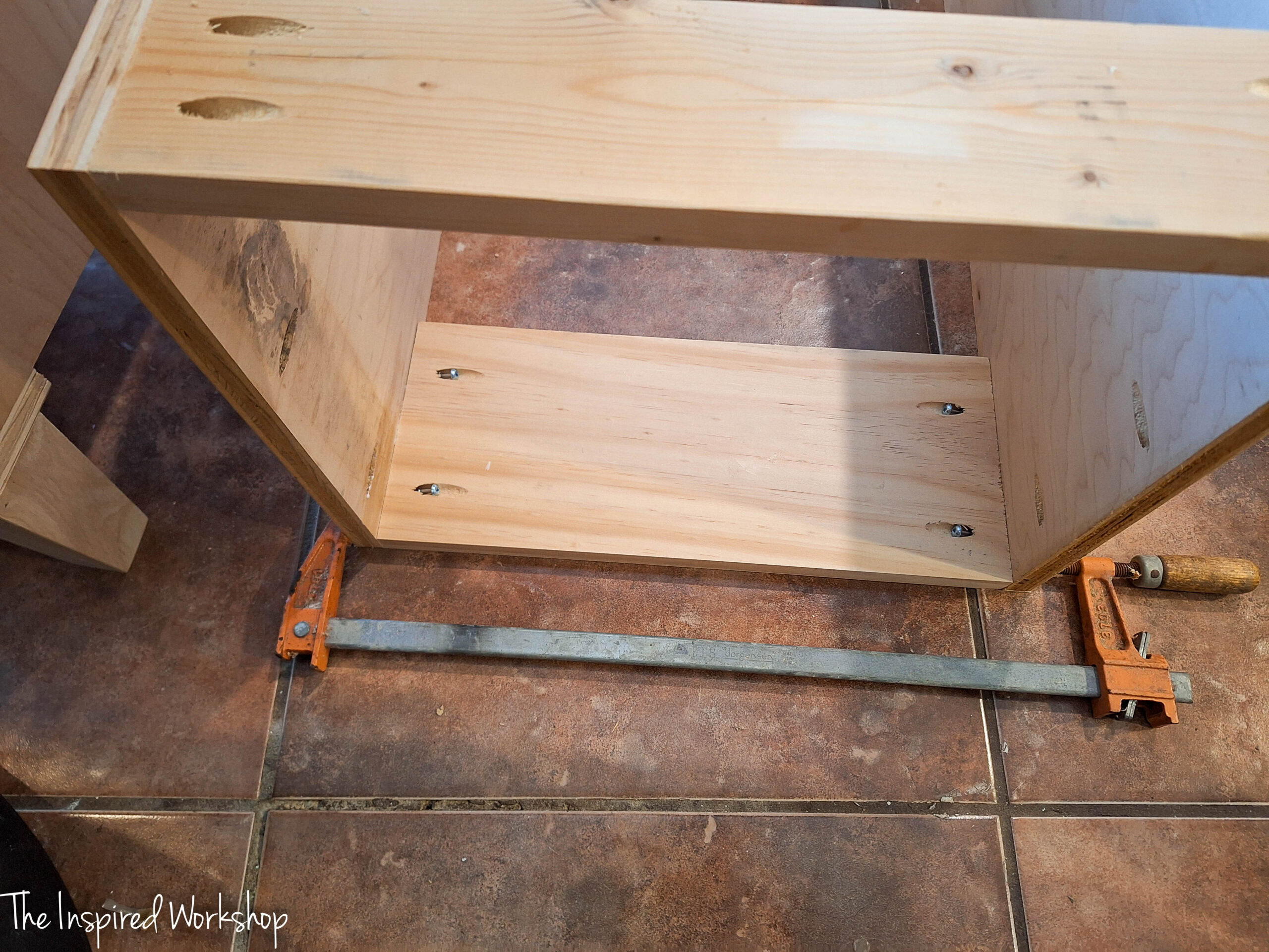 clamp on some wood of the shelves of the linen cabinet as it is being built