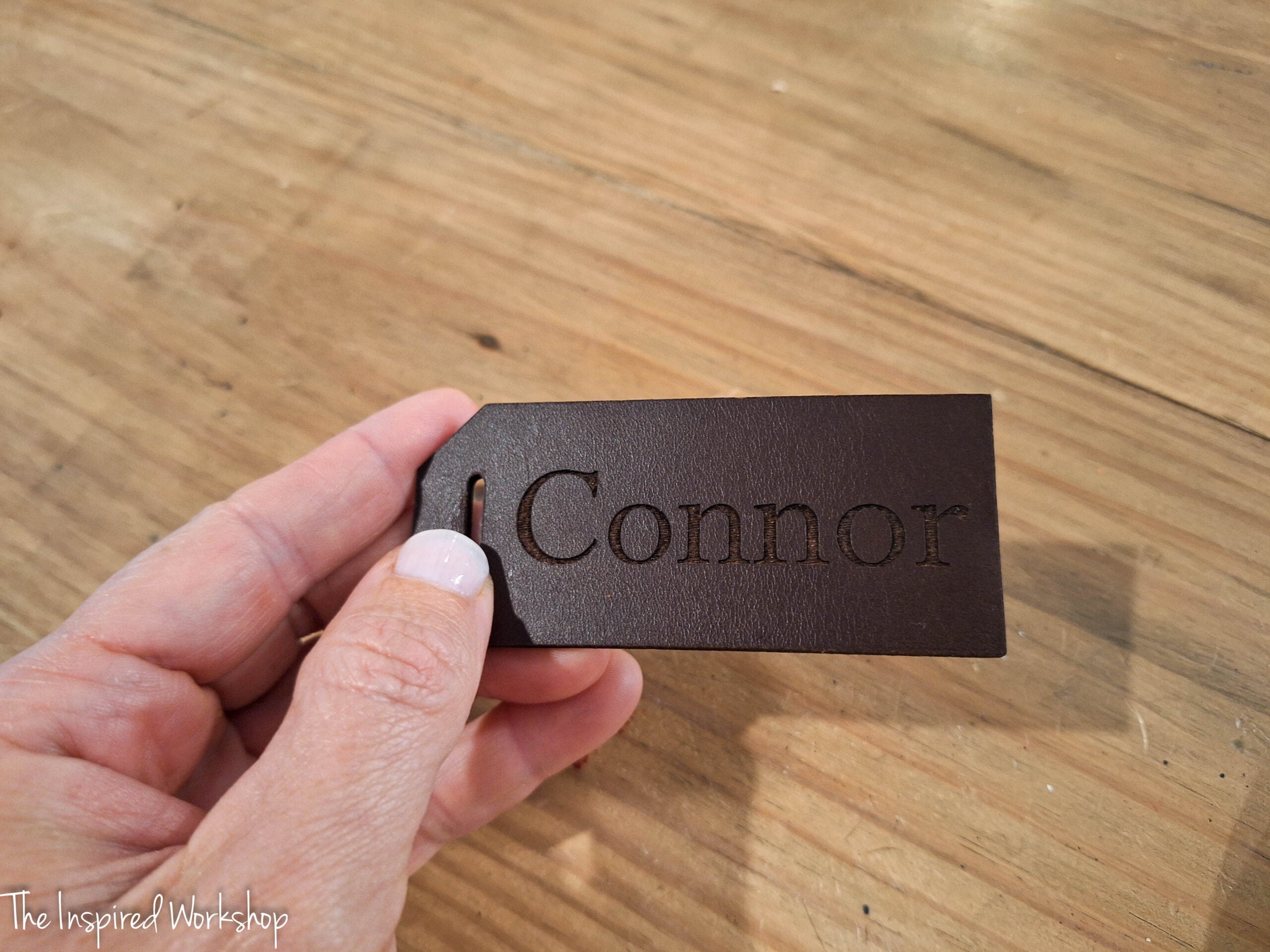 dark brown leather luggage tag engraved with the name connor