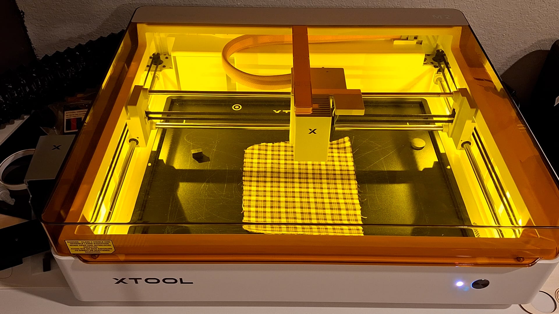 plaid fabric inside the xtool M2 being cut by the laser